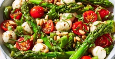 Grüner Spargel Salat mit Tomaten und Mozzarella auf einem Teller serviert