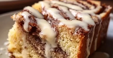 Leckeres Stück Zimtkuchen auf einem Teller mit Zimtstangen.