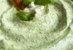 Avocado-Feta-Dip in einer Schüssel, garniert mit frischen Kräutern