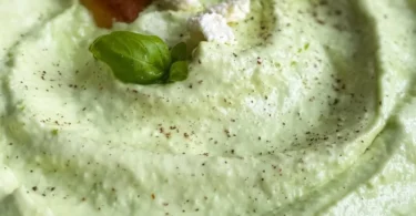 Avocado-Feta-Dip in einer Schüssel, garniert mit frischen Kräutern