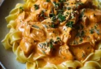 Cremiges Hähnchenragout mit Bandnudeln serviert auf einem Teller