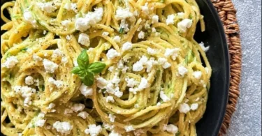 Pasta in Zucchini-Sauce serviert auf einem Teller mit frischen Kräutern