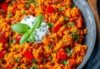 Schnelle Paprika-Reis-Pfanne mit Joghurtsoße auf einem Teller serviert