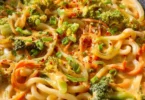 Udon Nudeln mit Erdnusssauce und Gemüse in einer Schüssel serviert